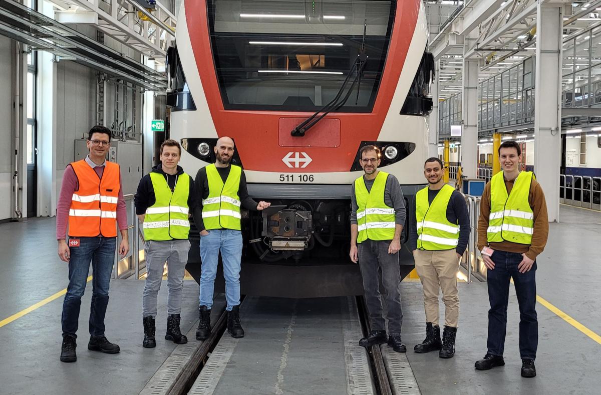 Six men stand in front of an SBB train