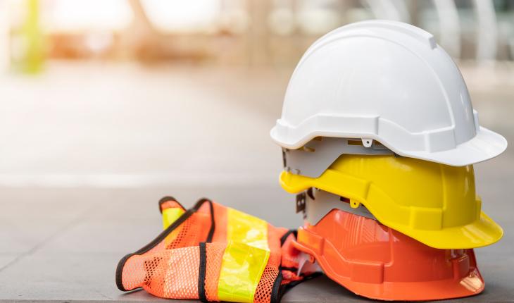 A pile of hard hats and a hi-vis safety vest.